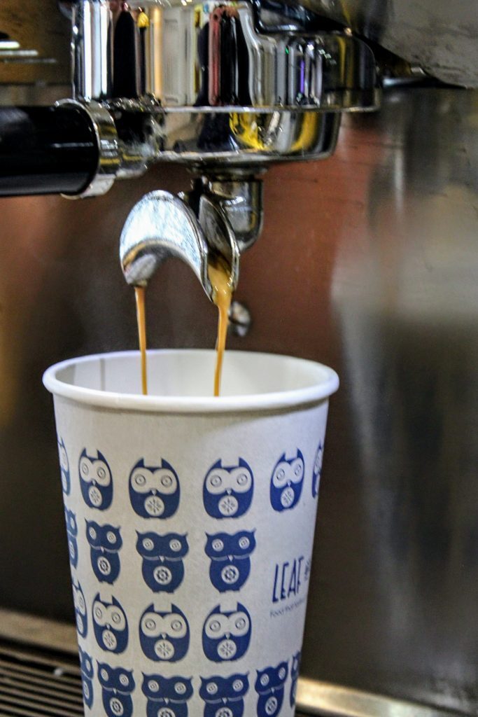 Espresso pouring into a navy owl-print Leaf and Bean cup.